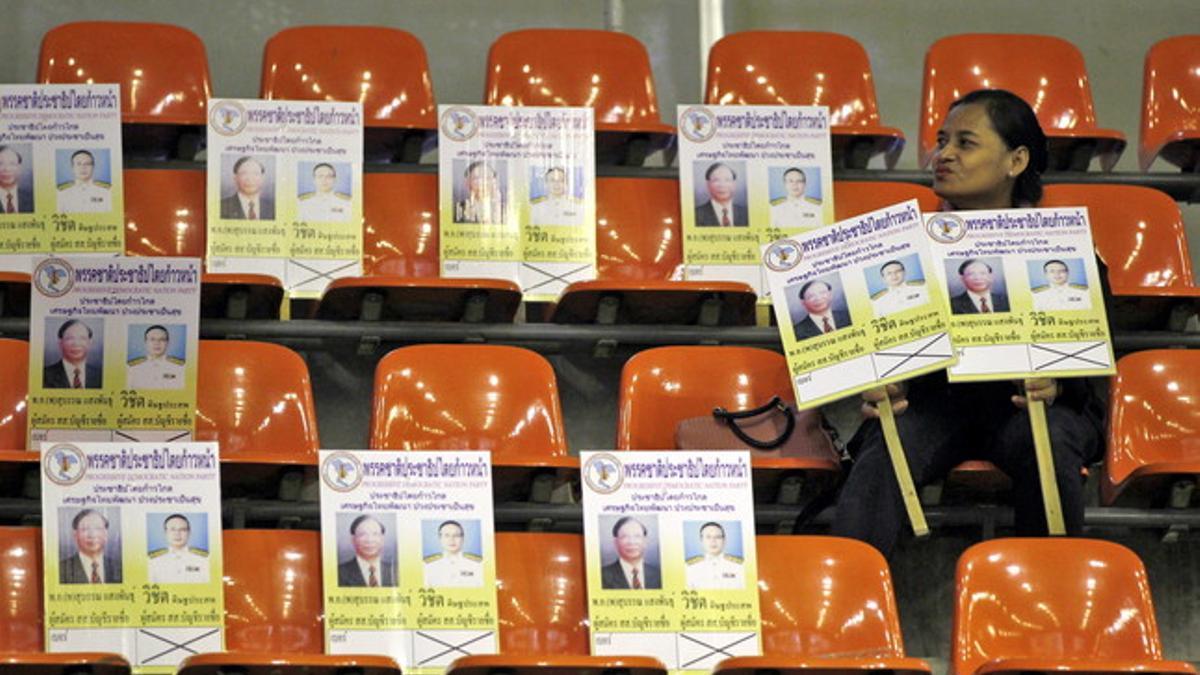 Una mujer del Partido Demócrata de Tailandia muestra carteles electorales durante el sorteo de los números para las elecciones en el Estadio Tailandés-Japonés en Bangkok (Tailandia).