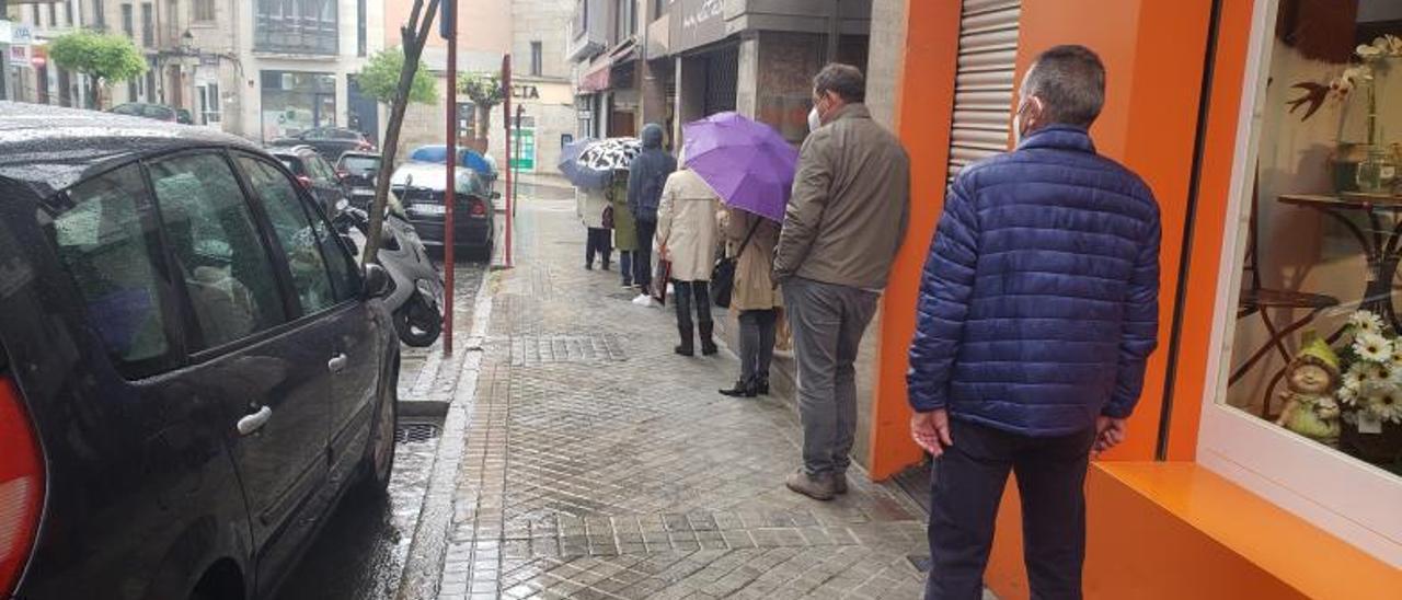 Espera de varias personas bajo la lluvia, para entrar a una pastelería de la ciudad. |   // F. CASANOVA