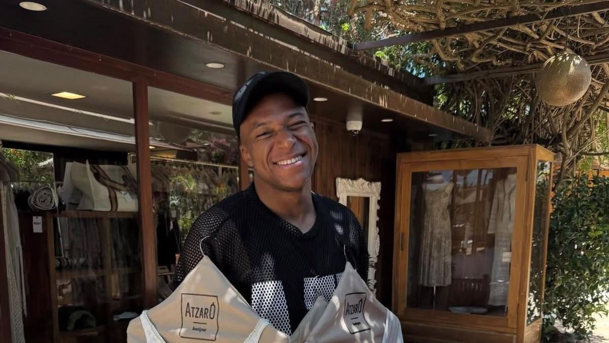 Mbappé posa sonriente y con varias prendas femeninas colgadas en perchas.