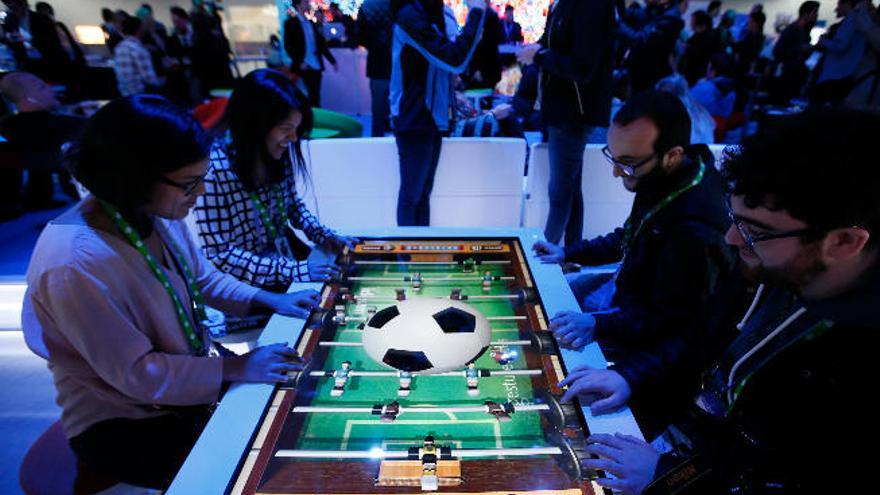 Varios asistentes al Mobile World Congress prueban un futbolín virtual.