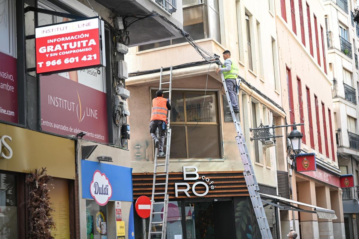 Unos operarios trabajan sobre uno de los cruces de calle volados de cable que se quieren retirar y prohibir