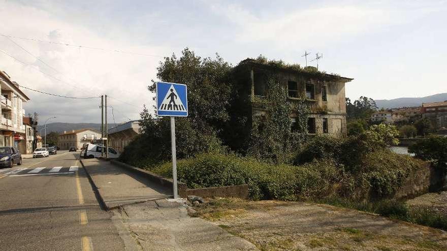 La vivienda de piedra, abandonada y cubierta de maleza, en pleno centro de A Ramallosa. // Ricardo Grobas