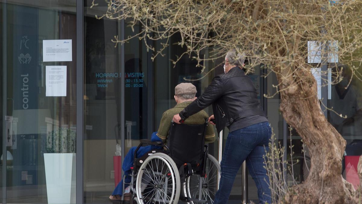 Un anciano en silla de ruedas entrando en una residencia.