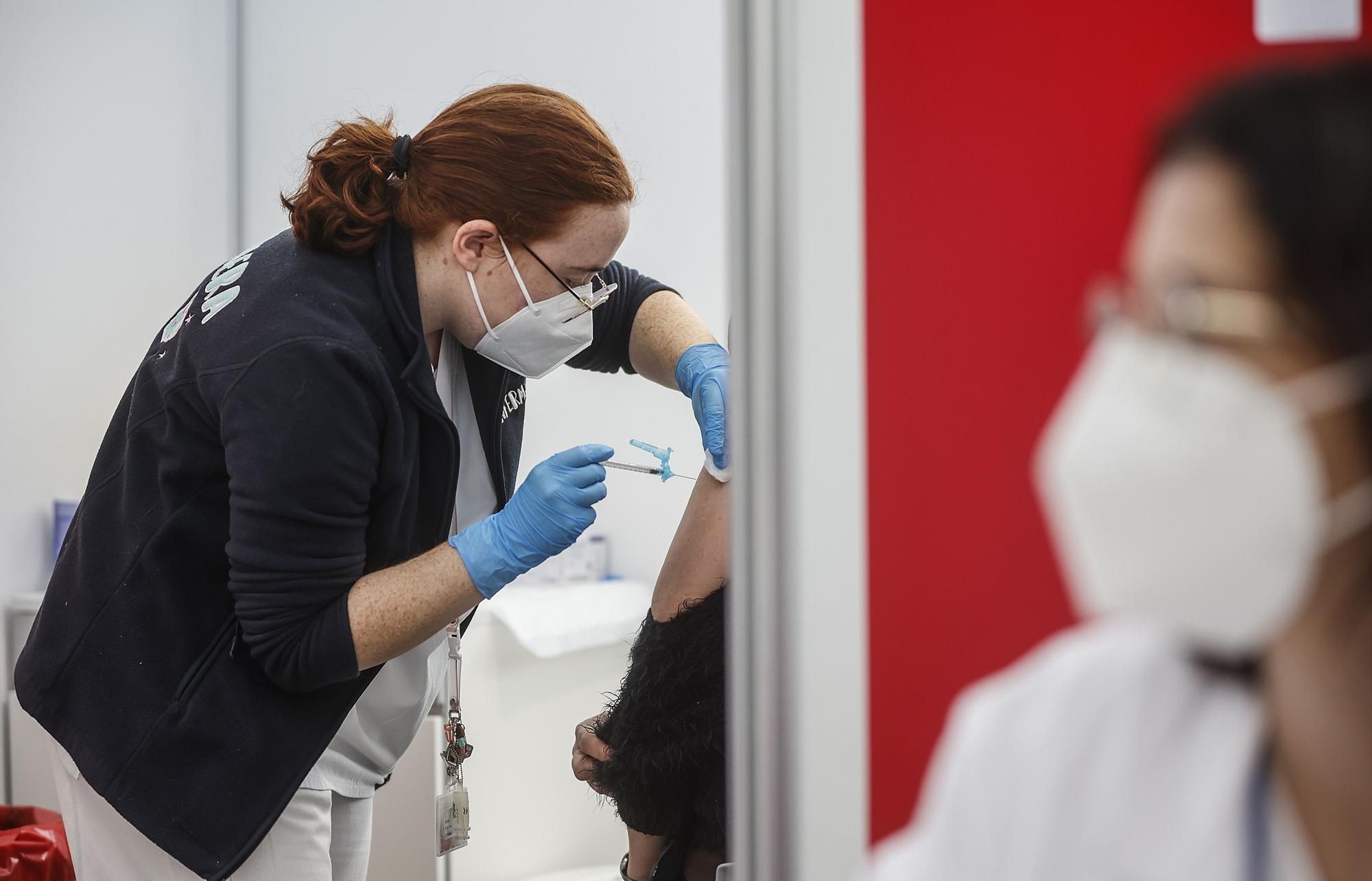 Una sanitaria vacuna a una persona con la tercera dosis de la vacuna de Moderna