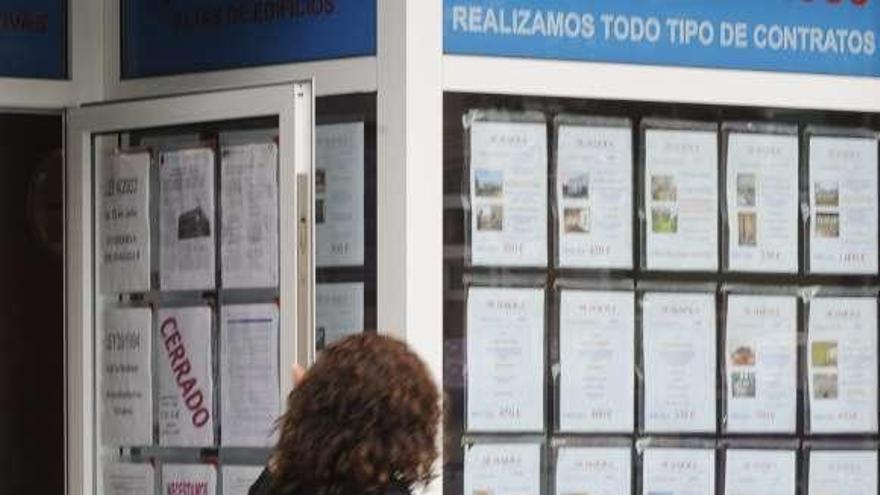 Una mujer pasa ante una agencia inmobiliaria.