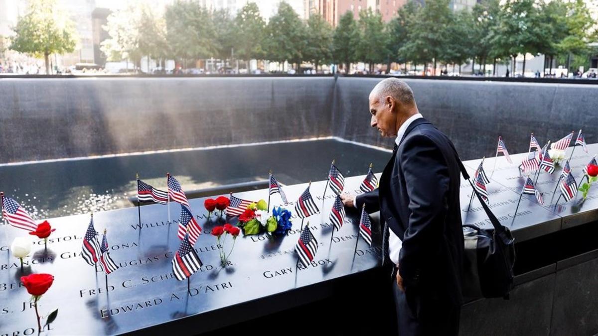 Un hombre acaricia los nombres grabados de los bomberos fallecidos en la parte sur del recordatorio a las víctimas del 11 de septiembre durante la ceremonia del 18º aniversario de la masacre.