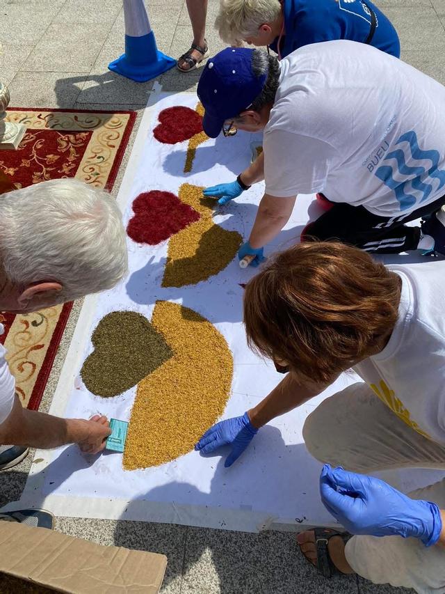 Integrantes de la Asociación Cunchas e Flores de Bueu trabajando en una alfombra de arte efímero.