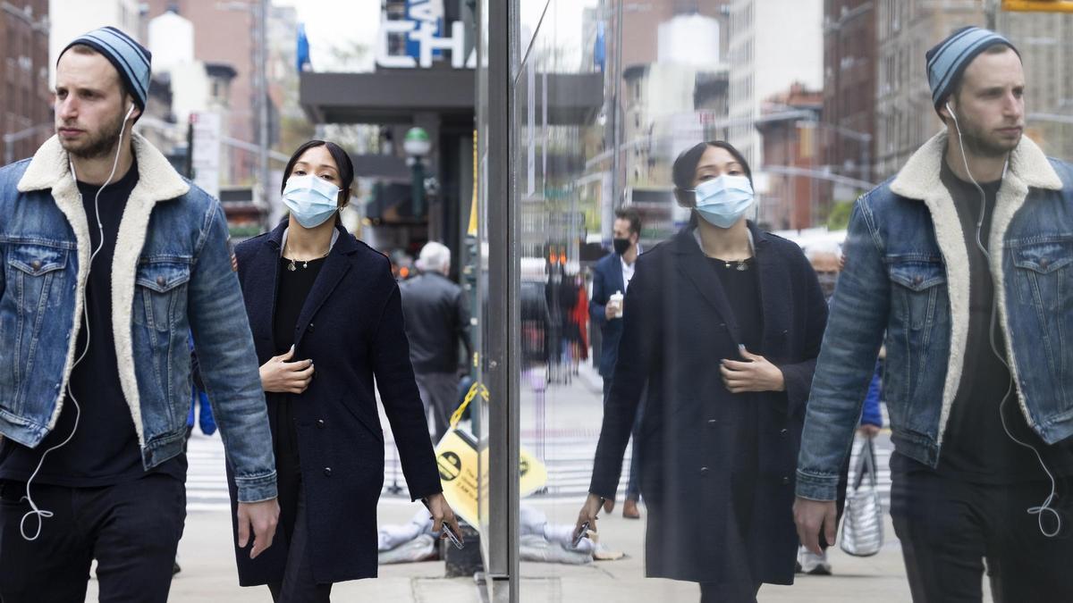 Dos jóvenes con y sin mascarilla caminan por las calles de Nueva York