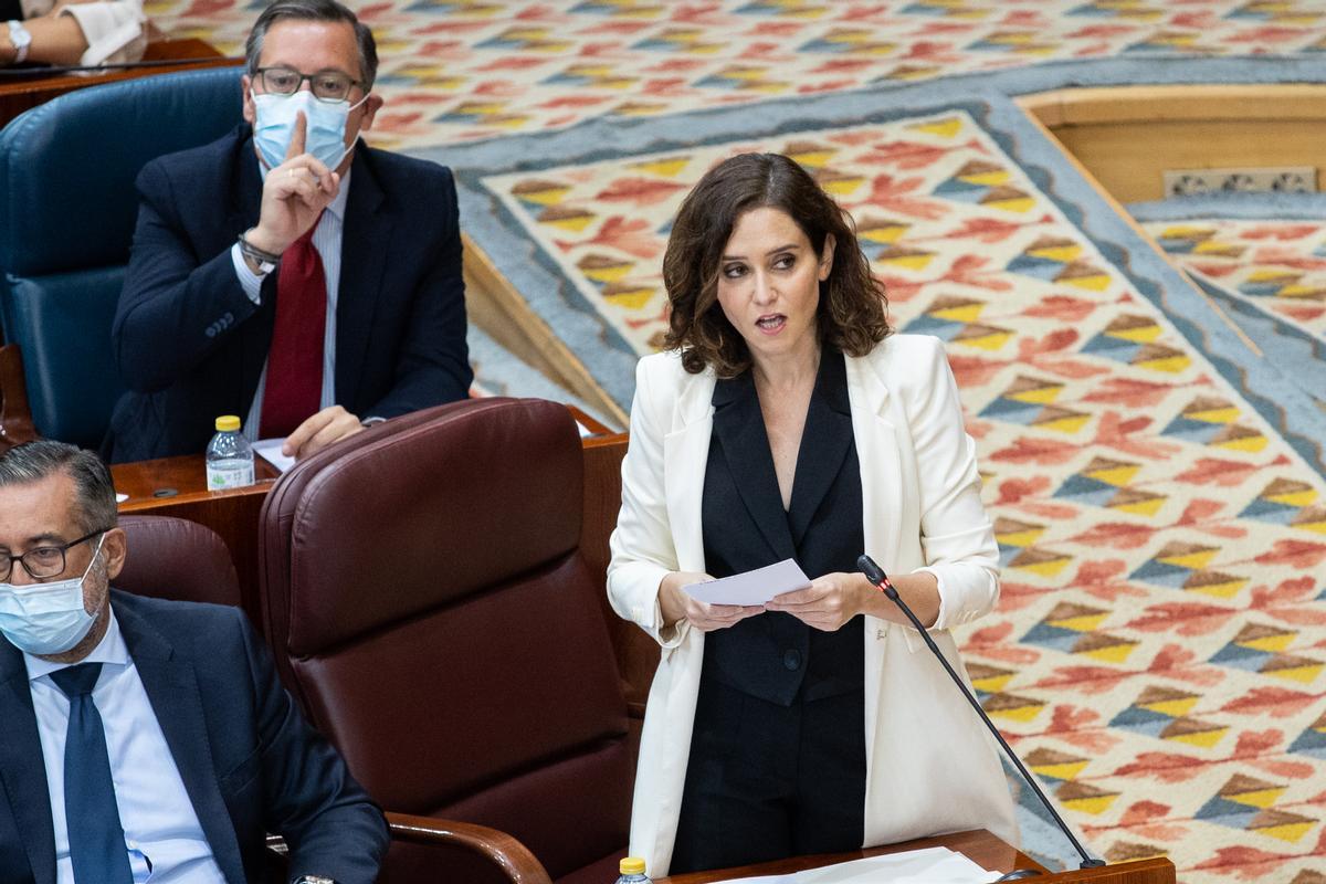 Díaz Ayuso, y Alfonso Serrano (al fondo), en un Pleno de la Asamblea.