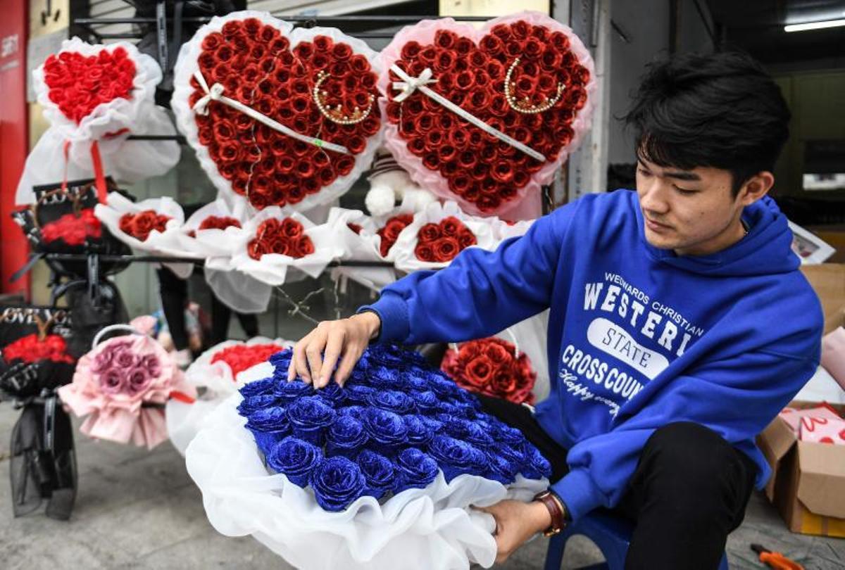 Una vendedora que vende ramos de flores y chocolates para el Día de San Valentín espera a los clientes en su puesto callejero en Hanoi