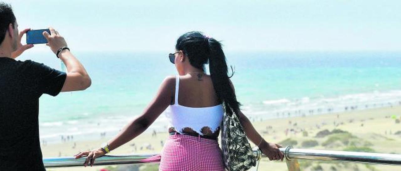 Una pareja de turistas observa el estado de una playa desde una terraza.