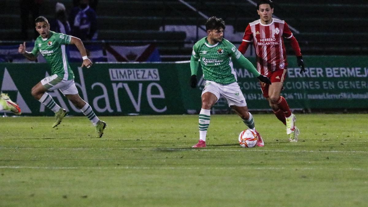 Teto controla el balón en presencia de un rival.