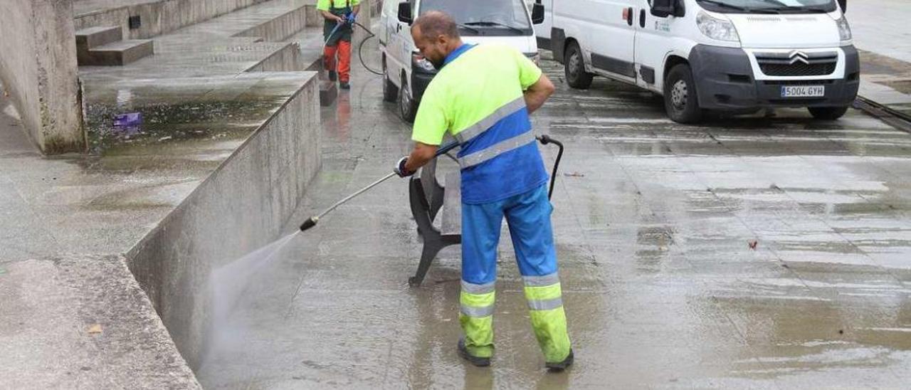 Un operario de la empresa realizando labores de limpieza con agua en una de las zonas de la ciudad, junto a uno de los vehículos. // Iñaki Osorio