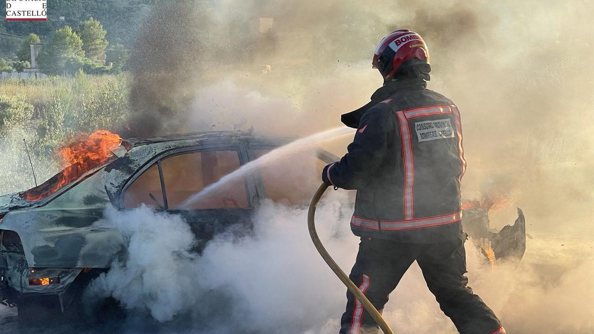 Un bombero apaga el fuego en el vehículo incendiado.