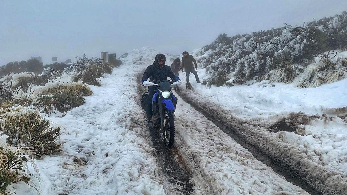 Un motoristra pasa por un sendero abierto en la nieve en el Parque Nacional del Teide, ayer.