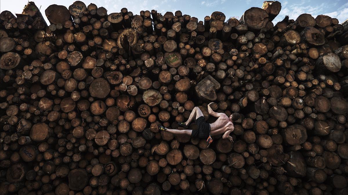 Primer premio del World Press Foto en la categoría de Deportes.Georg sube a una pila de troncos mientras entrena para búlder, en Kochel am See, Baviera, Alemania, el 15 de septiembre. El búlder implica escalar pequeñas formaciones rocosas y cantos rodados de no más de seis metros de altura, sin cuerdas ni arneses.