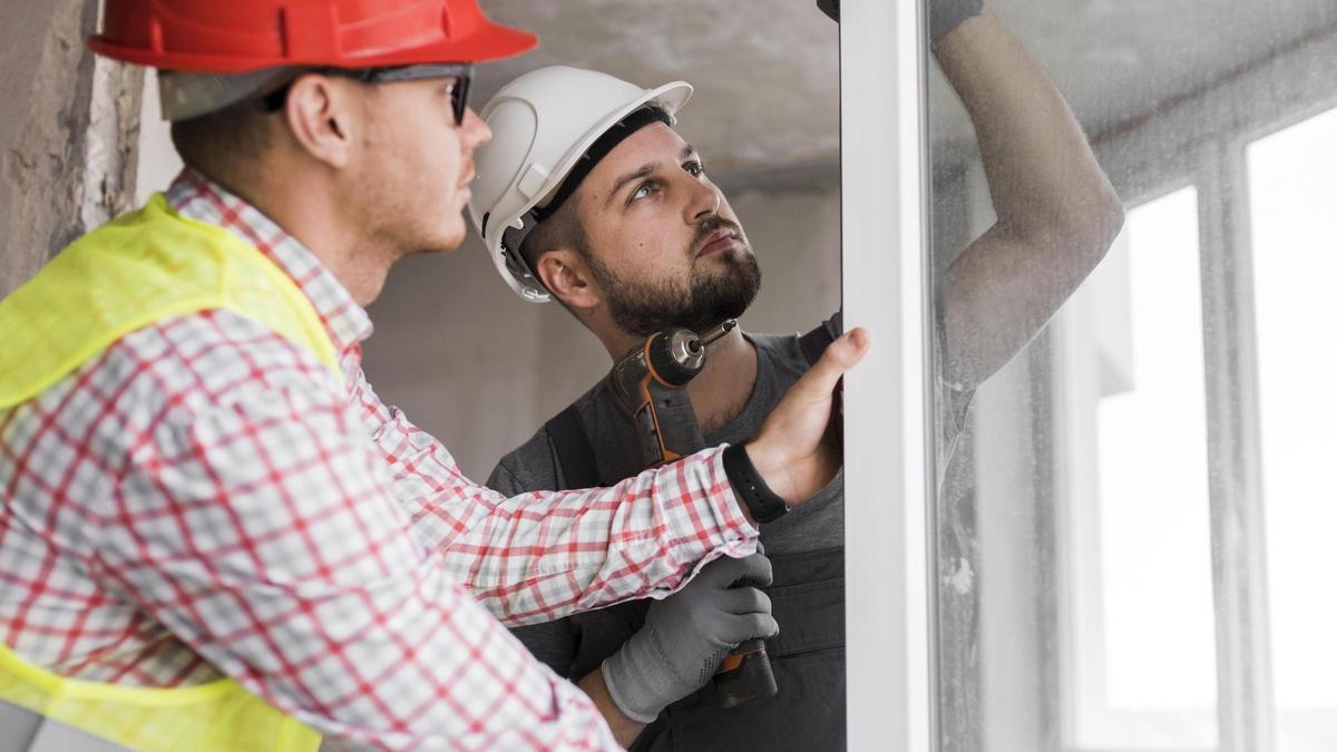 Dos operarios revisan la colocación de una puerta