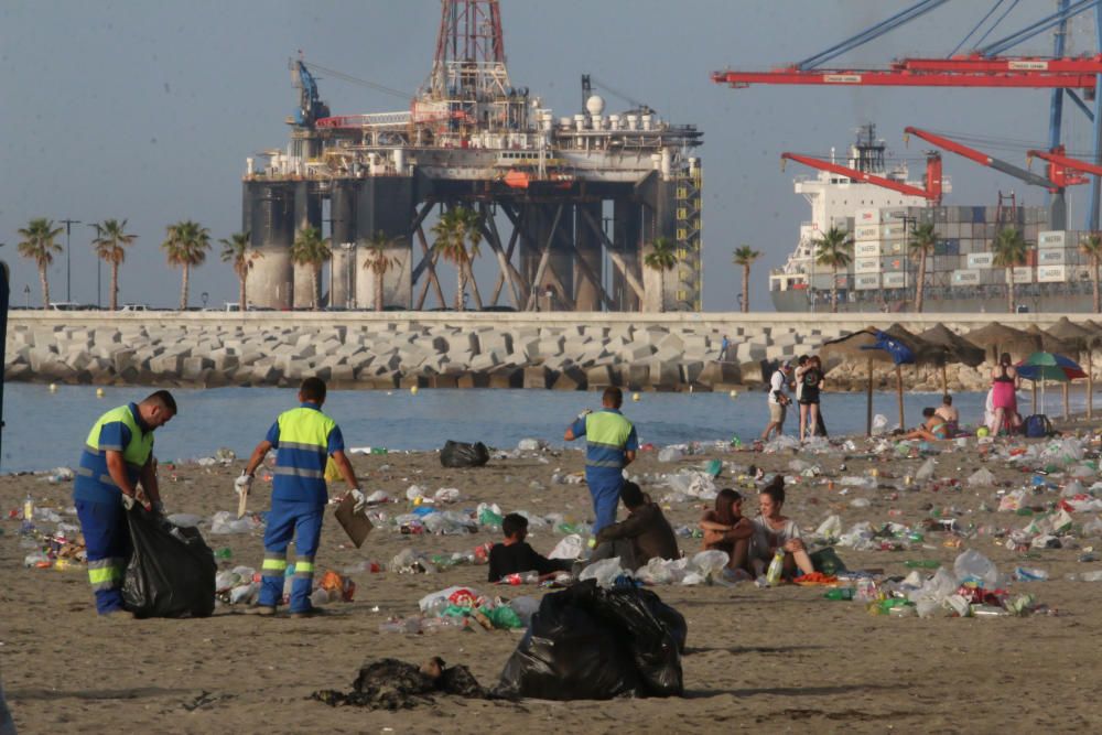 Los operarios de los servicios de limpieza trabajan para dejar la playa en óptimas condiciones tras una larga noche de fiesta en la arena