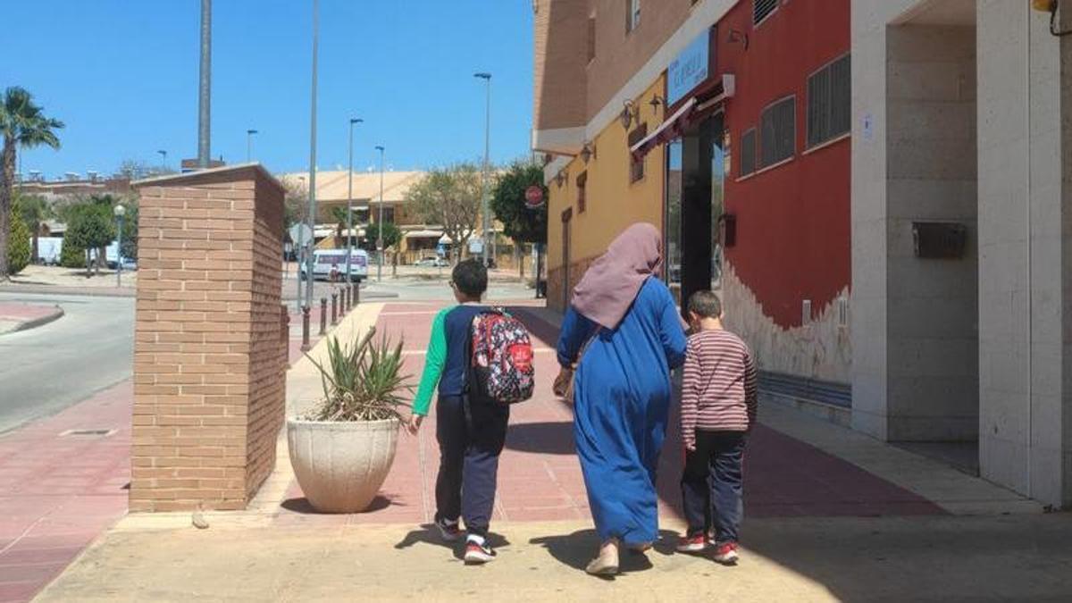 Una mujer anda por una calle de Molina de Segura en Murcia con sus hijos tras recogerlos del colegio.