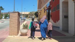 Una mujer anda por una calle de Molina de Segura en Murcia con sus hijos tras recogerlos del colegio.