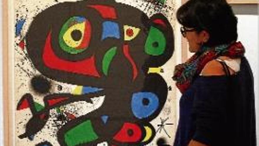 Una dona mira una de les acolorides obres de Miró.