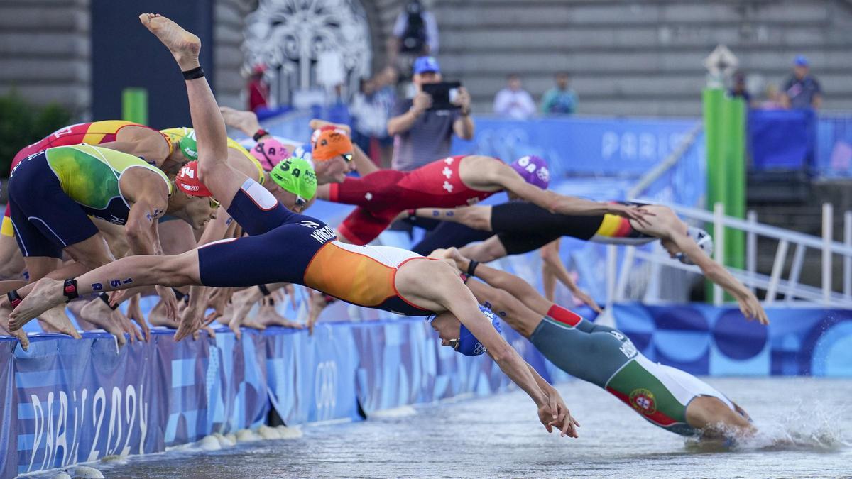 El holandés Mitch Kolkman, en primer término, se zambulle en el agua para el inicio de la prueba de triatlón de relevos mixtos en los Juegos Olímpicos de Paris 2024,