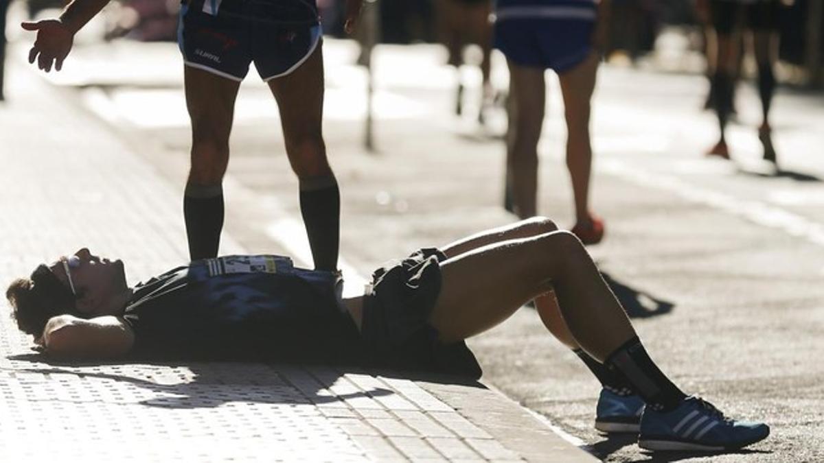 Un participante descansa en la acera tras acabar la Behobia-San Sebastián este domingo.