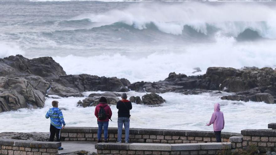 Gente contempla el fuerte oleaje desde el paseo de Baiona. // Alba Villar