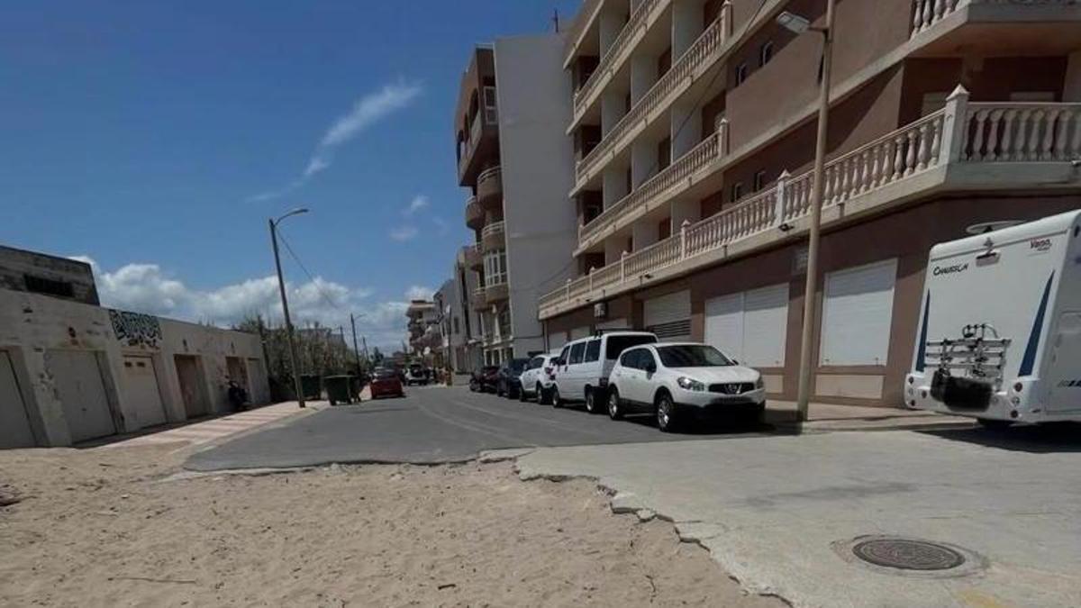 Tramo de una calle que acaba en la arena y, a la derecha, una caravana aparcada.
