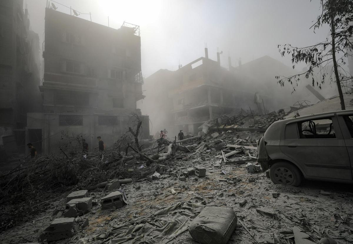 Palestinos caminan por una zona destruida por bombardeos israelíes en la ciudad de Gaza, este lunes.