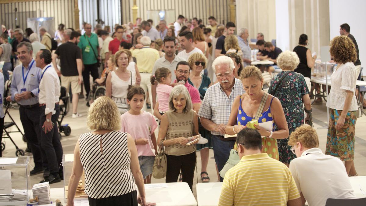 Ciudadanos votan en el colegio electoral de San Esteban, en Murcia. A la izquierda, dos apoderados del PP: Juan María Vázquez y Ramón Sánchez-Parra.
