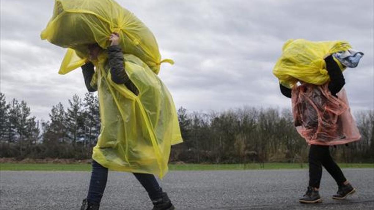 Refugiados llegan bajo la lluvia a un campo próximo a Idomeni (Grecia), ayer.