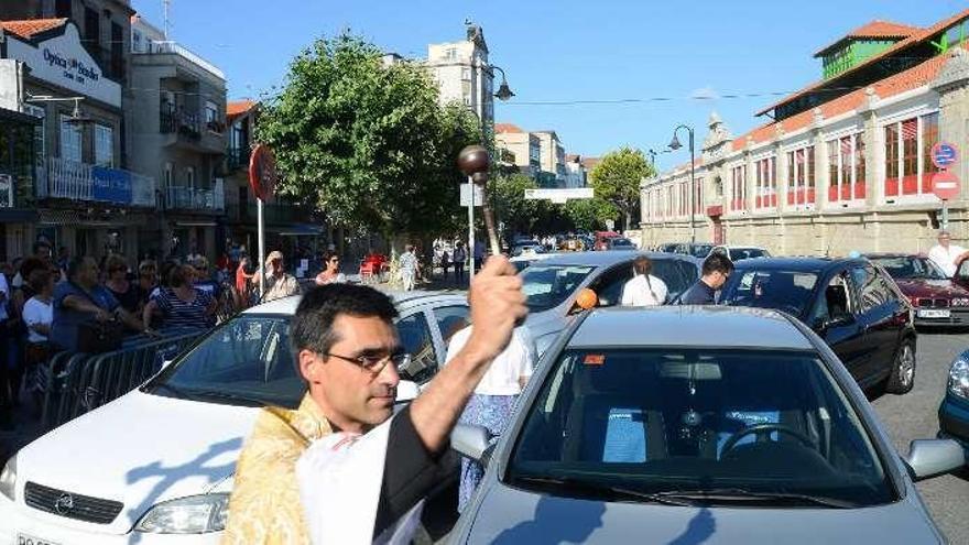 El párroco de Cangas en una bendición anterior de coches. // G.N.