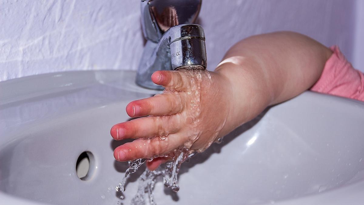 Un niño se lava las manos en un grifo