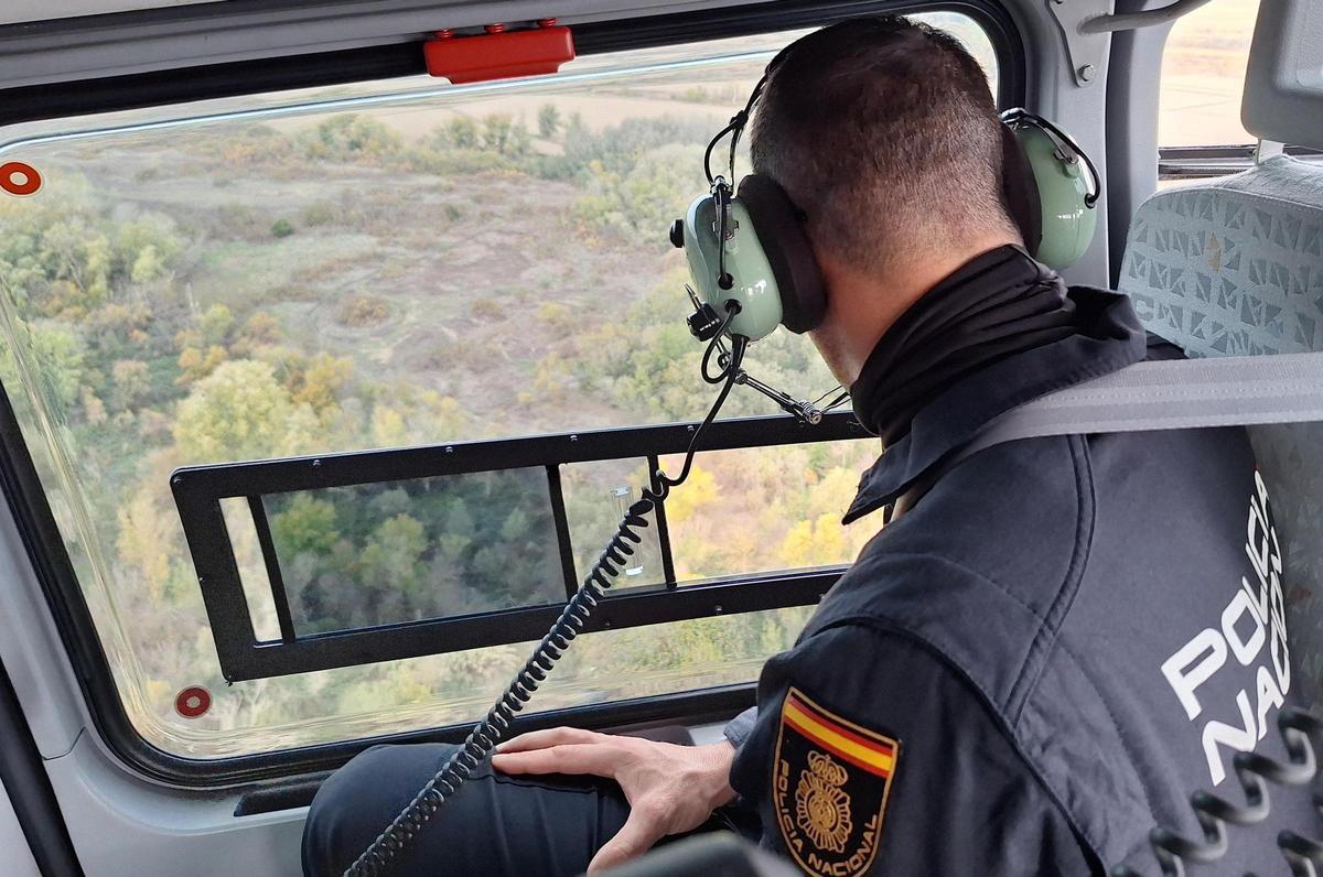 Un efectivo de la Policía Nacional realiza una búsqueda desde el helicóptero en una desaparición reciente.