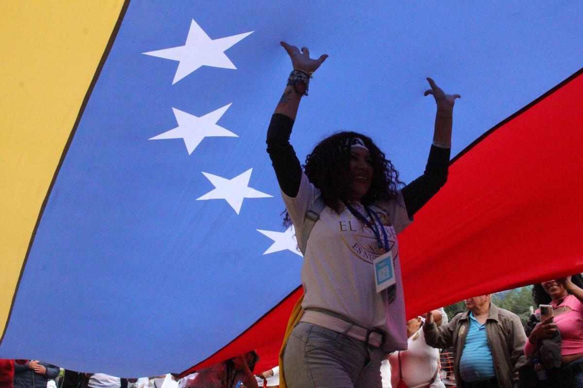 Una mujer camina debajo de una bandera durante la marcha "por la paz y la libertad" en Venezuela realizada en Lima (Perú) el pasado 6 de diciembre de 2025.