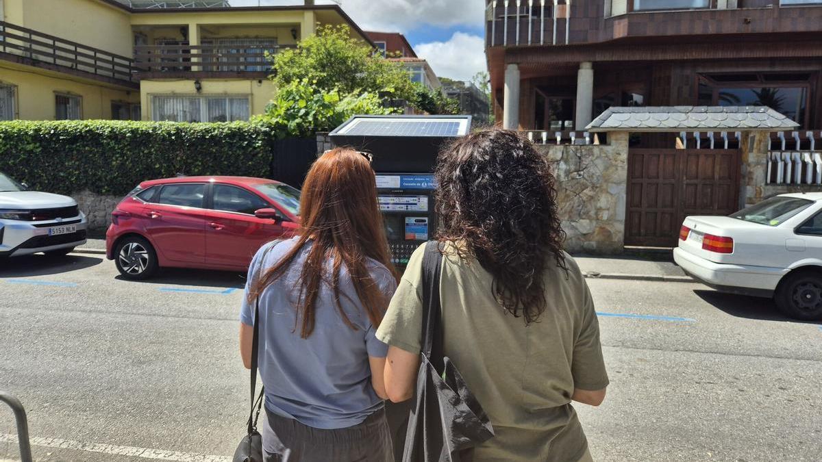 Dos usuarias pagan el estacionamiento regulado en un parquímetro de la playa de Santa Cristina, en Oleiros.