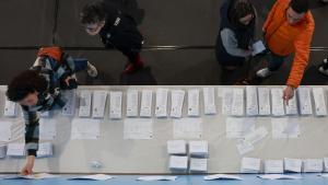 Varias personas escogen papeletas para ejercer su derecho al voto en el pabellón polideportivo Ames en A Coruña durante la jornada electoral en Galicia