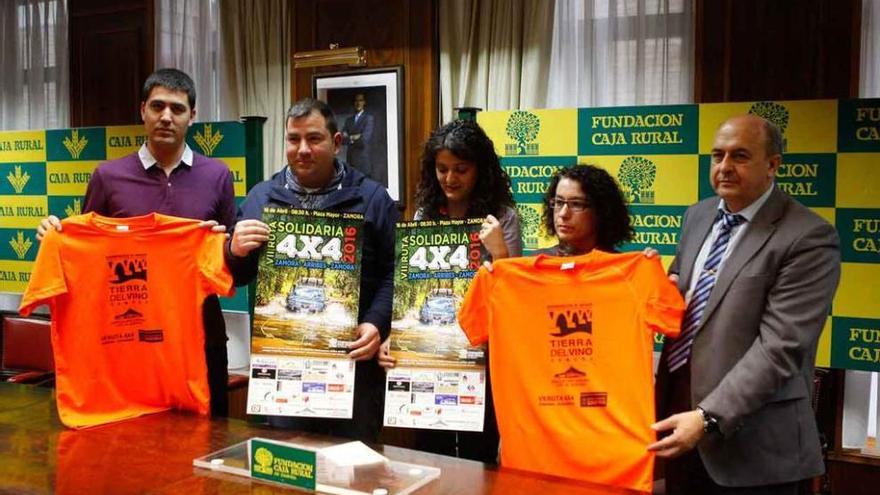 Organizadores y colaboradores del evento posan con las camisetas y carteles promocionales.