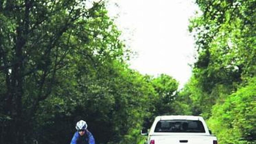 visitantes. Una ciclista australiana desciende el Angliru tras haber alcanzando la cima, con el vehículo que llevaba a Guillén a la derecha. | j. r. silveira