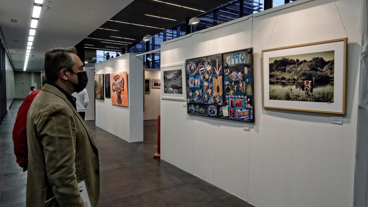 Dos personas observan varias de las obras que forman parte de la exposición colectiva.