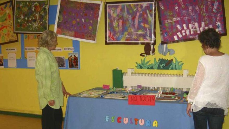 Dos responsables del centro de educación infantil admiran las esculturas y pinturas realizadas por los alumnos. Foto