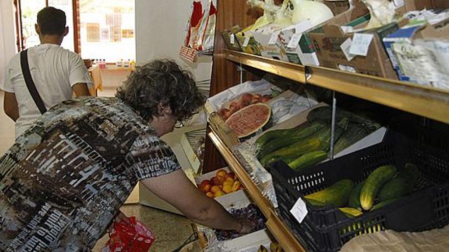 Una mujer selecciona fruta que se puede adquirir en la asociación.