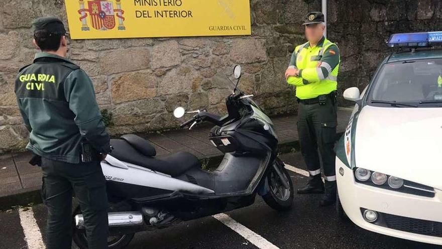 Dos agentes, junto a la moto recuperada en el operativo.  // Guardia Civil