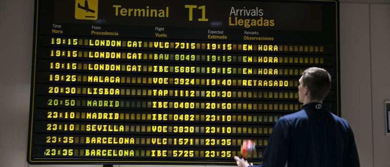 Un usuario consulta el panel de llegadas del aeropuerto de Asturias.