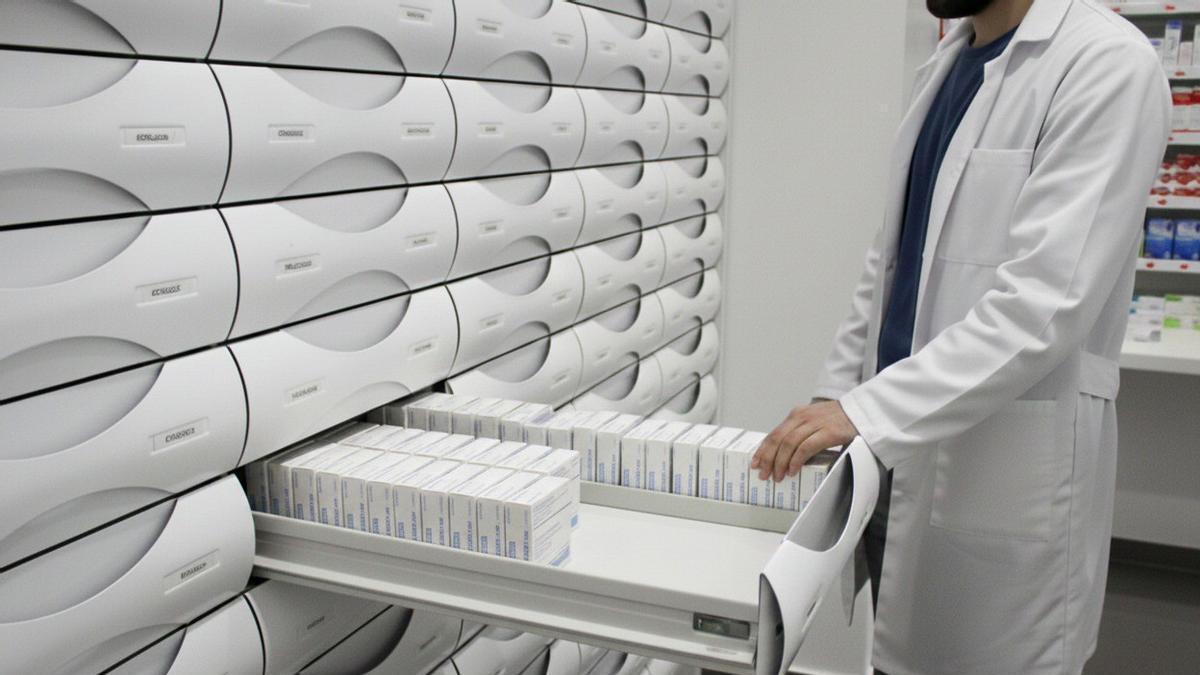 El empleado de una farmacia extrae medicamentos de un sistema de cajones automatizados.