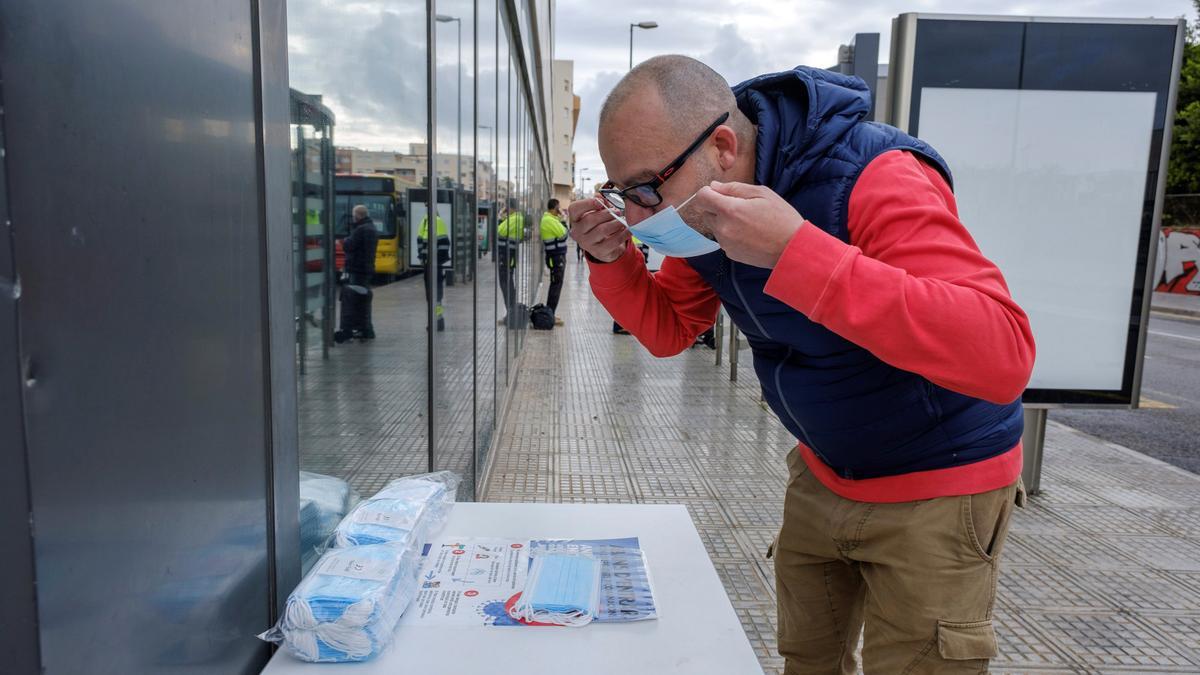 Un hombre se coloca una mascarilla antes de entrar en un interior.