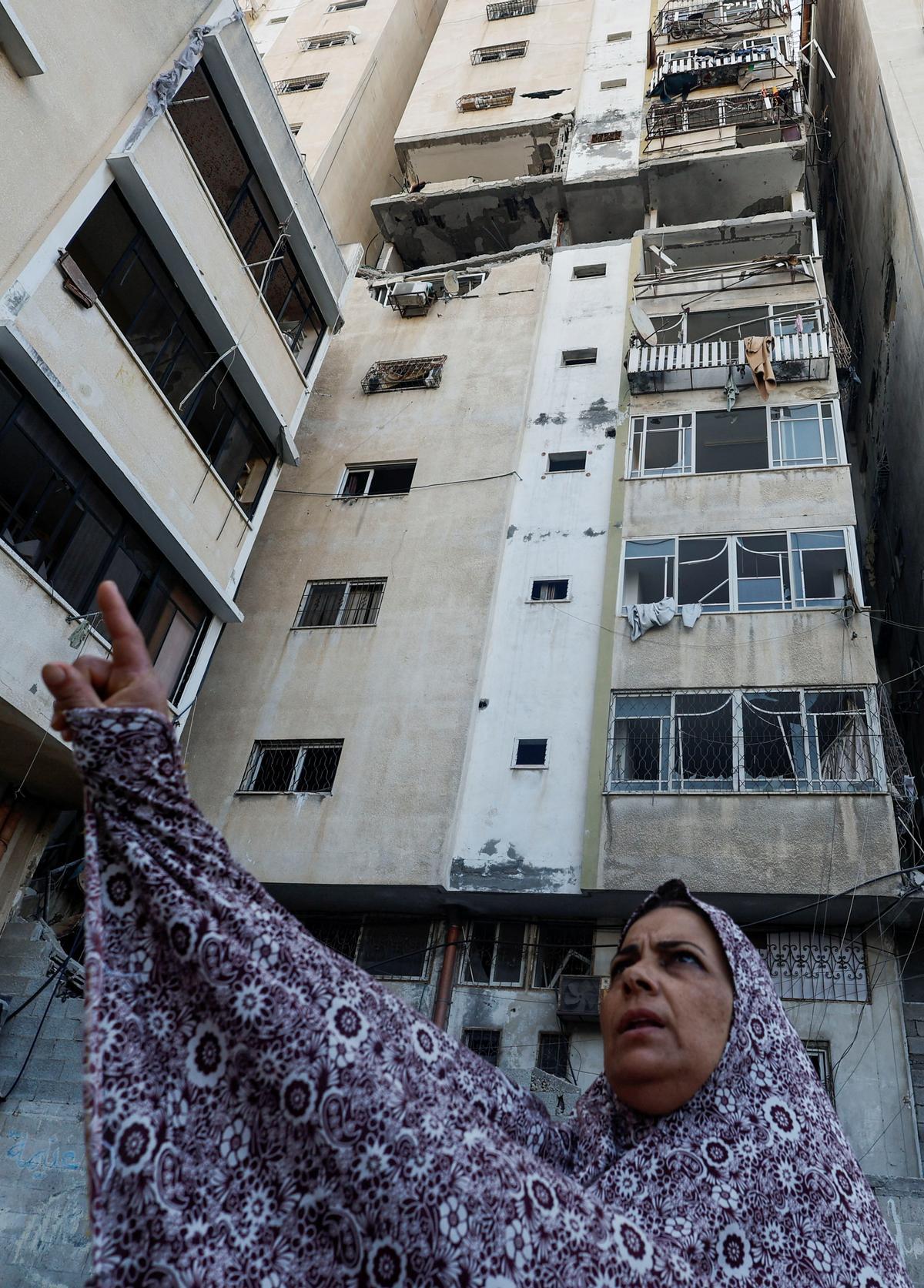 Una mujer hace un gesto junto a un edificio dañado donde el alto comandante del grupo militante de la Yihad Islámica Tayseer al-Jaabari fue asesinado en ataques israelíes