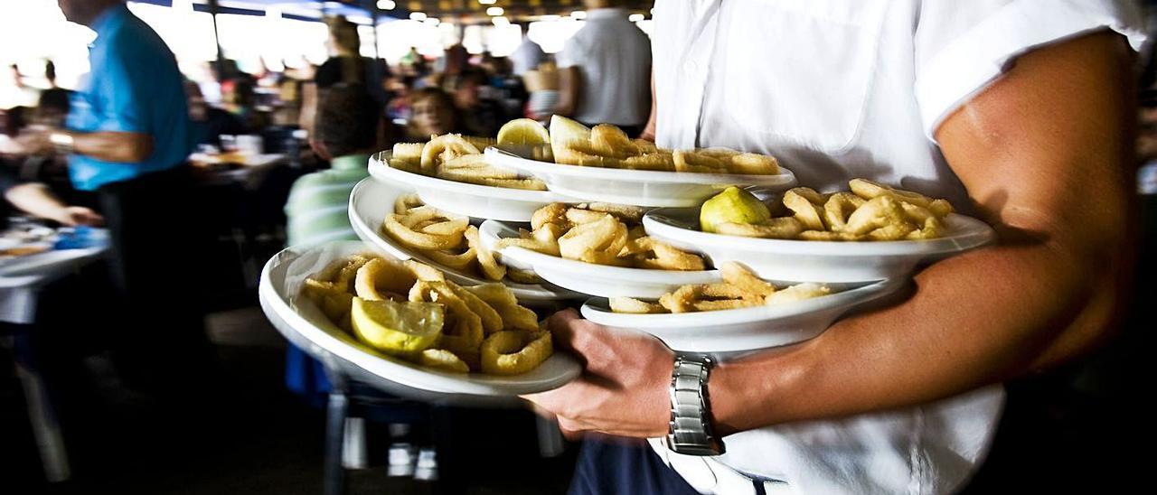 Un camarero cargado de platos en un chiringuito.