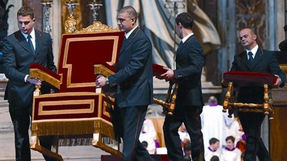 Unos asistentes mueven la silla del Papa en la basílica de San Pedro, ayer.